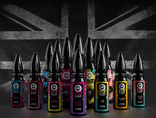Variety of RIOT Nic Salt vape bottles with colorful labels in front of UK flag background